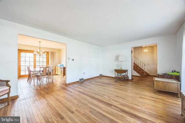 living room featuring stairway, light wood finished floors, a chandelier, and baseboards