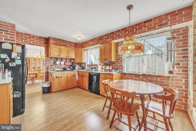 kitchen with black appliances, light wood-style floors, light countertops, brick wall, and hanging light fixtures