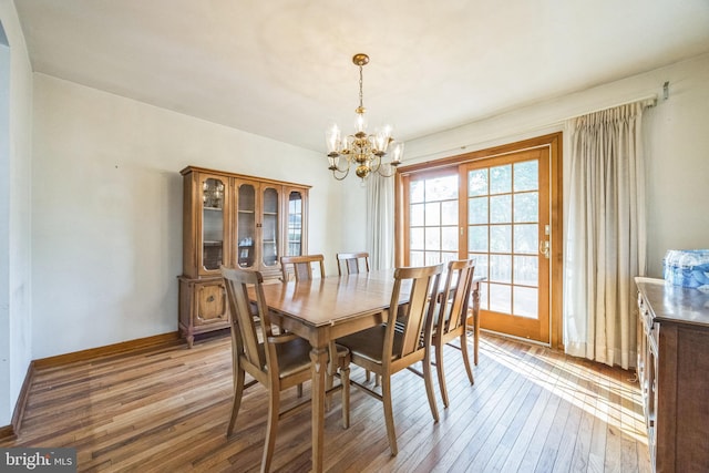 dining area with a chandelier, light wood-style floors, and baseboards
