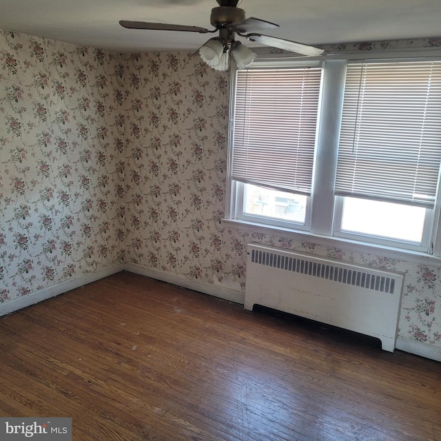 empty room with ceiling fan, hardwood / wood-style flooring, baseboards, and radiator