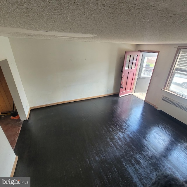 interior space featuring radiator heating unit, wood finished floors, baseboards, and a textured ceiling