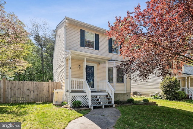 traditional-style house featuring central AC unit, a front lawn, and fence