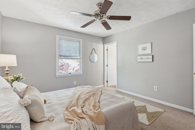 bedroom featuring baseboards, a ceiling fan, a textured ceiling, and light carpet