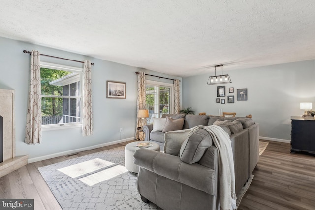living area featuring baseboards, a textured ceiling, wood finished floors, and visible vents