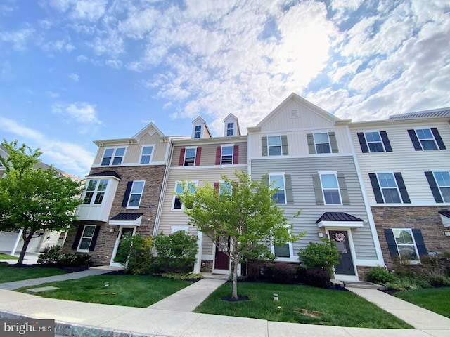 townhome / multi-family property featuring board and batten siding, stone siding, and a front yard