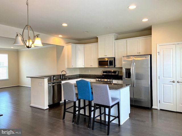 kitchen featuring a peninsula, recessed lighting, dark wood-type flooring, white cabinetry, and appliances with stainless steel finishes