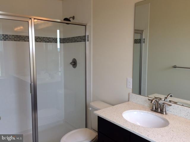 full bathroom with vanity, a stall shower, and toilet
