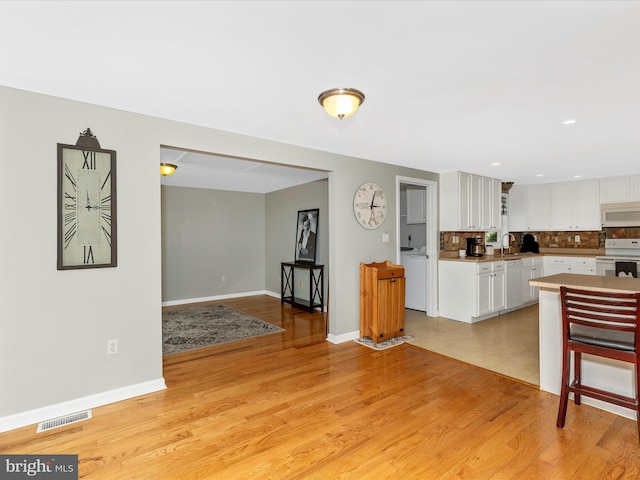 13240 Edgemont Rd, Smithsburg, MD 21783 - kitchen featuring white appliances, a sink, white cabinetry, decorative backsplash, and light wood finished floors