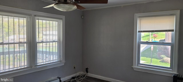 spare room with a baseboard heating unit, a wealth of natural light, a ceiling fan, and baseboards
