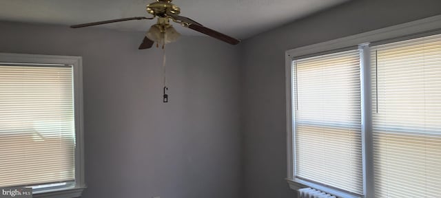 interior space with radiator heating unit, a ceiling fan, and a healthy amount of sunlight