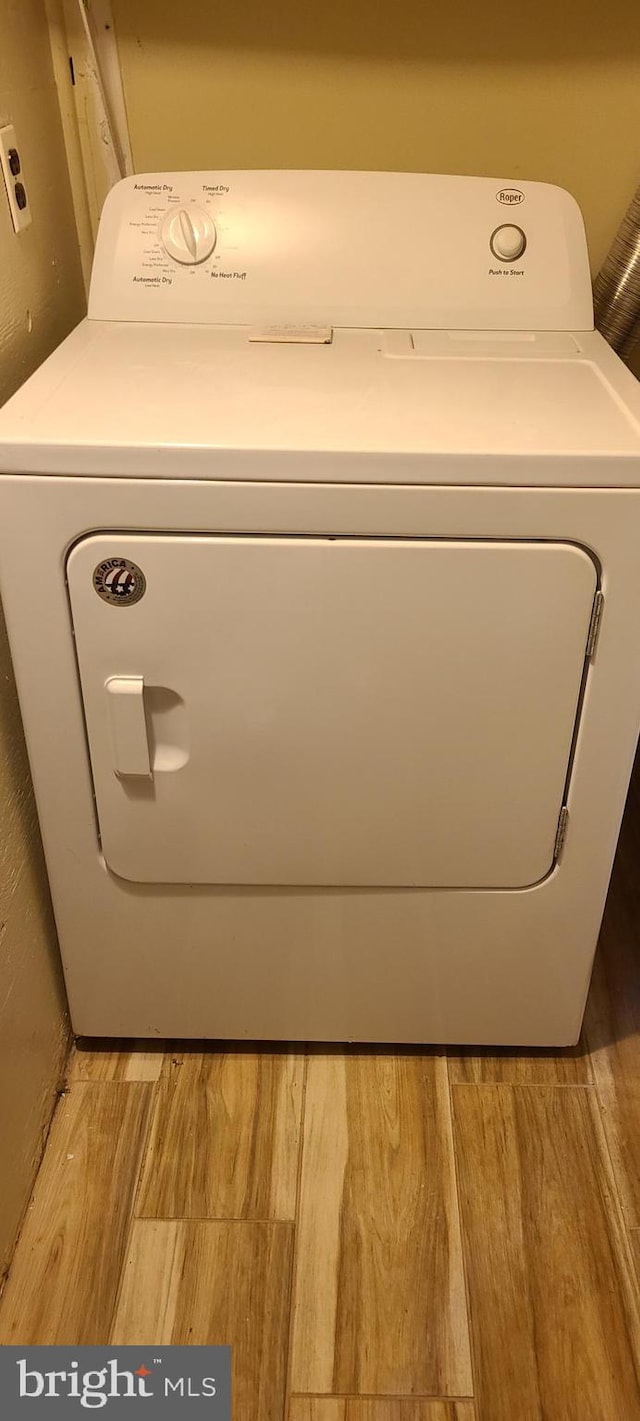 clothes washing area with washer / dryer, wood finished floors, and laundry area