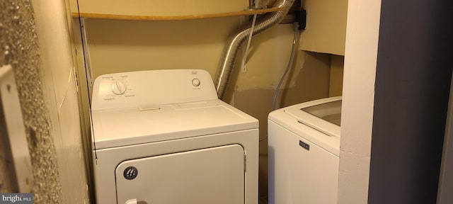 clothes washing area featuring separate washer and dryer and laundry area