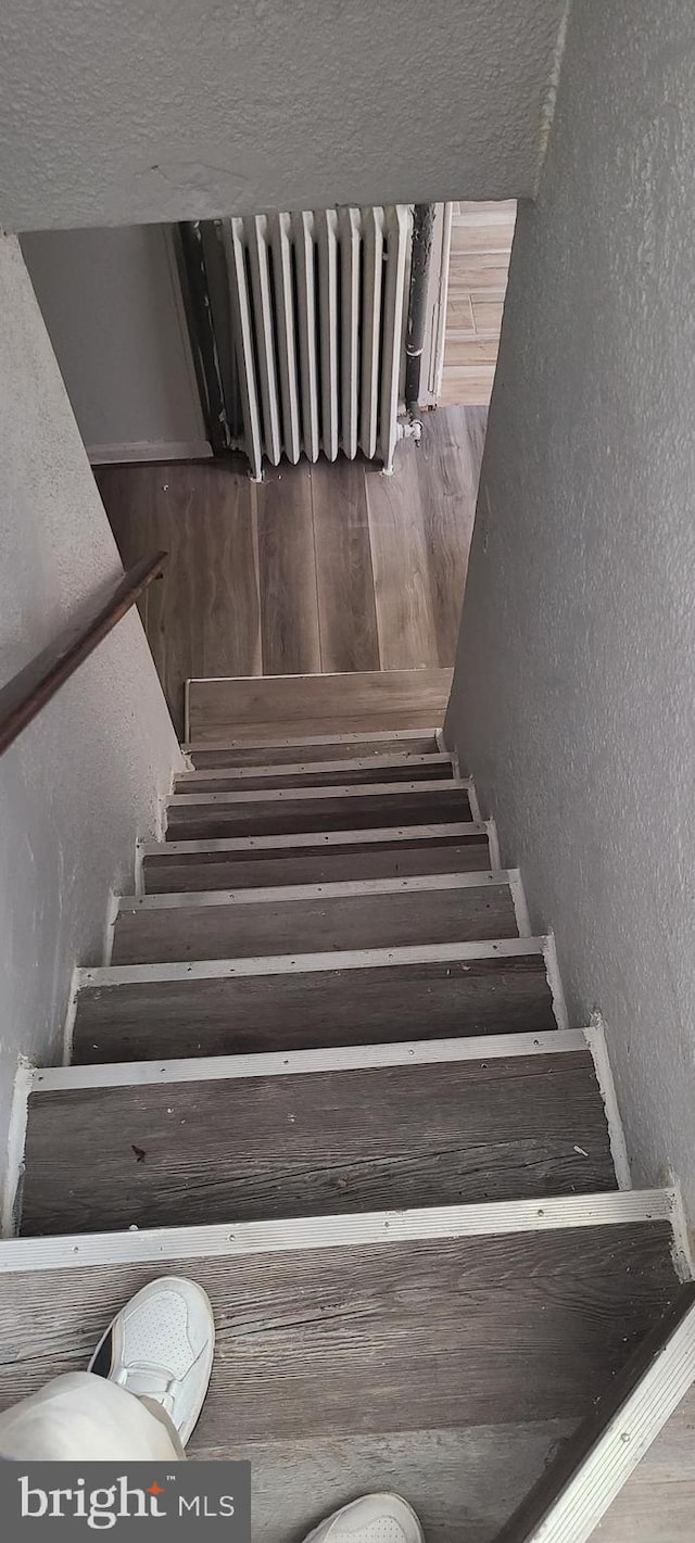 stairs featuring a textured wall and a textured ceiling