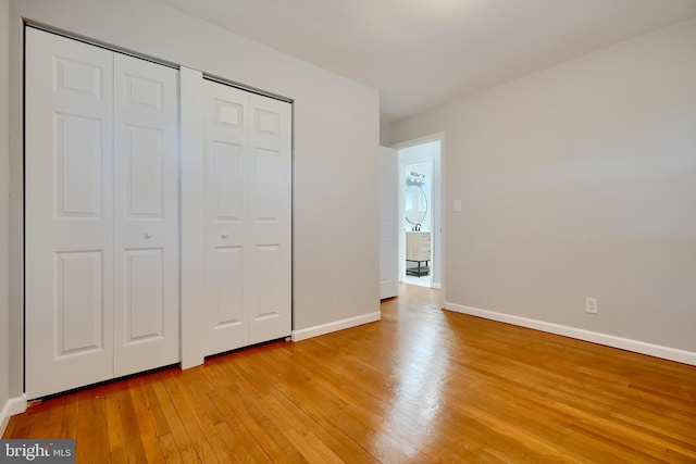 unfurnished bedroom with baseboards, a closet, and light wood-type flooring