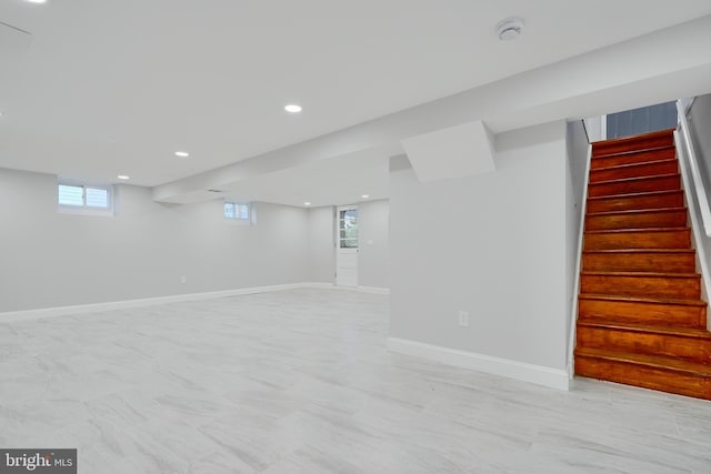 basement featuring recessed lighting, baseboards, stairs, and plenty of natural light