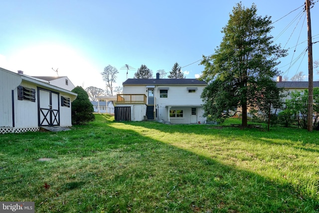 rear view of property featuring stairway, a lawn, an outdoor structure, and fence