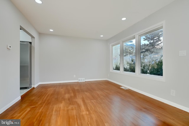 spare room featuring recessed lighting, visible vents, light wood finished floors, and baseboards