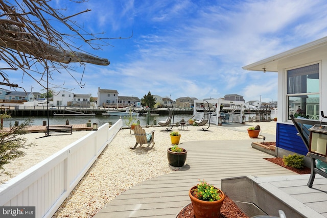 wooden terrace featuring a water view, a residential view, and a dock