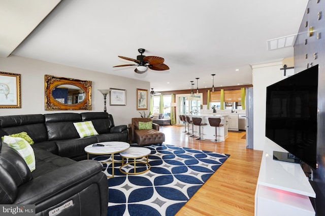 living room featuring a ceiling fan, visible vents, recessed lighting, and light wood finished floors