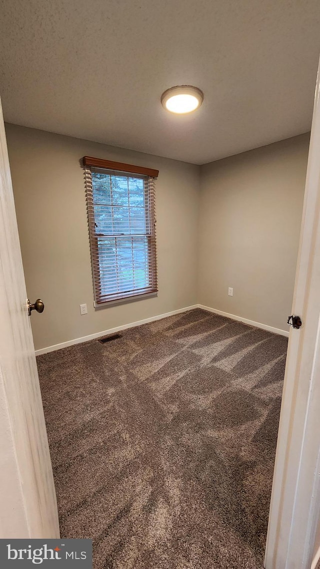 carpeted spare room with baseboards and visible vents