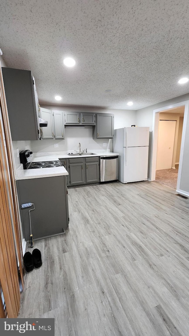 kitchen featuring stainless steel dishwasher, recessed lighting, a sink, and freestanding refrigerator