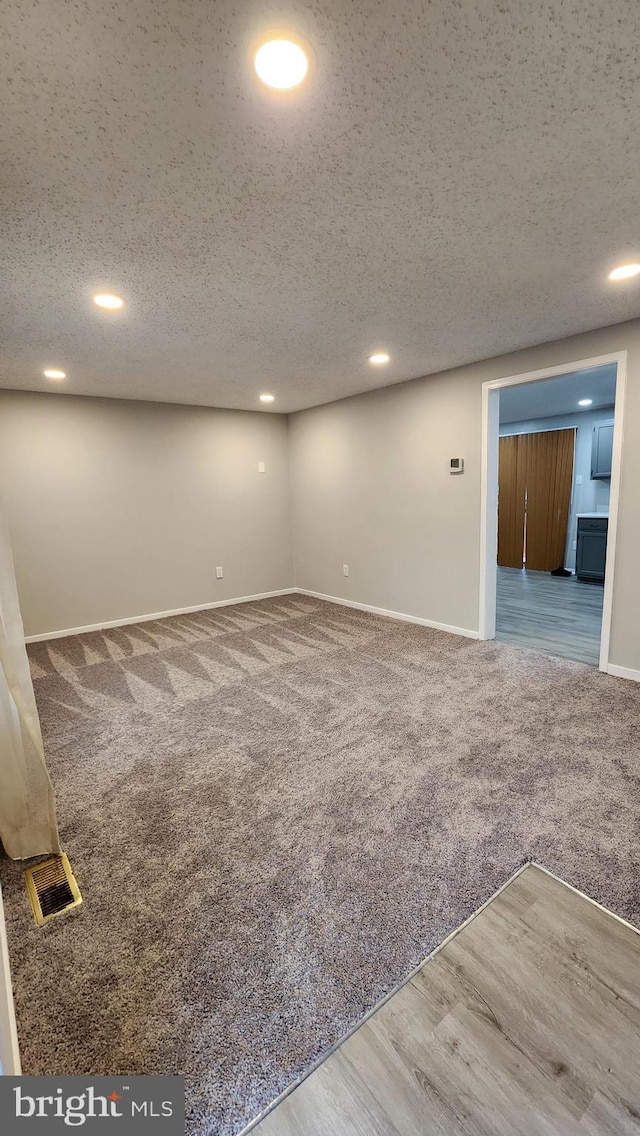 basement with recessed lighting, a textured ceiling, and carpet