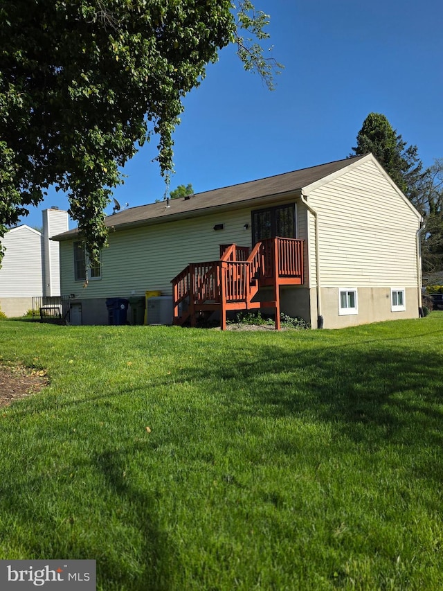 rear view of house with a wooden deck and a yard