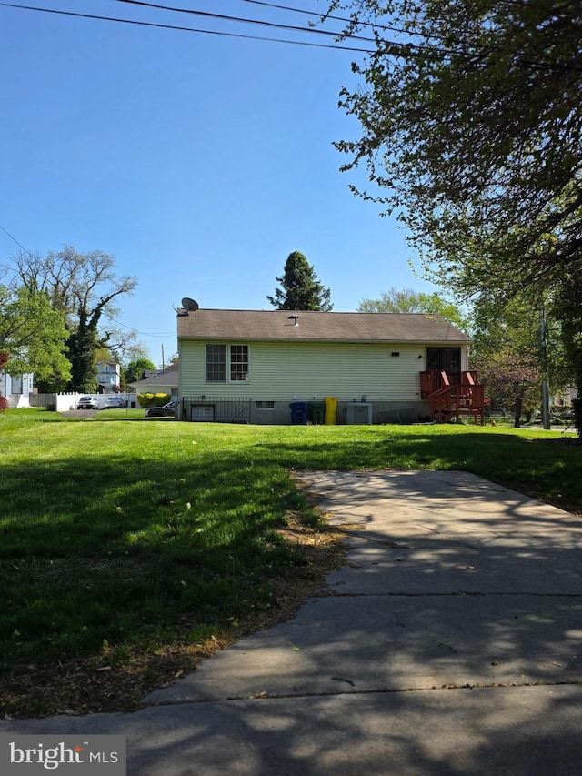 view of side of property featuring a lawn and a wooden deck