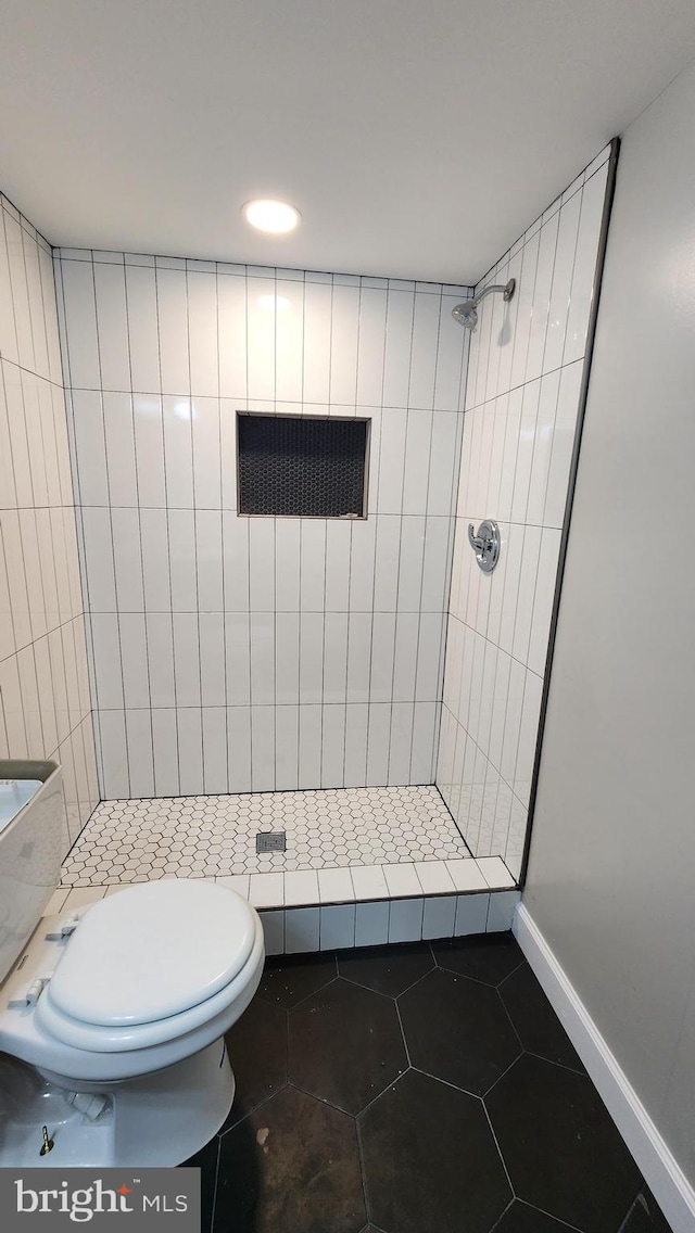 bathroom with toilet, a stall shower, tile patterned floors, and baseboards