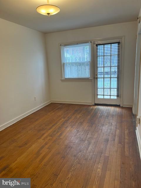 spare room featuring dark wood finished floors and baseboards