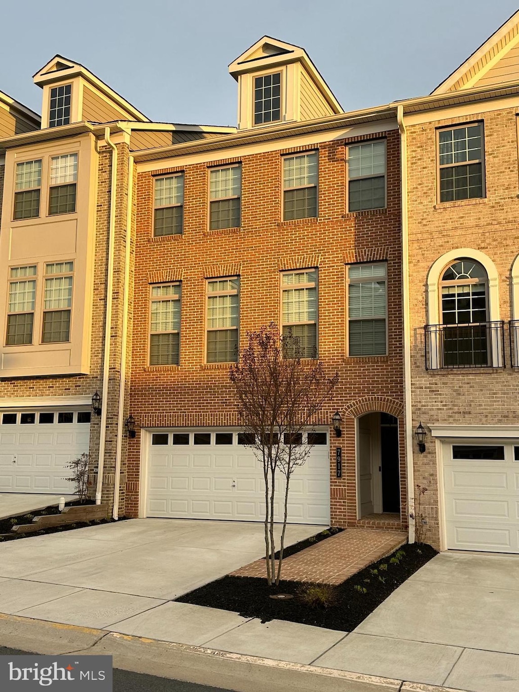 view of property featuring brick siding, an attached garage, and driveway