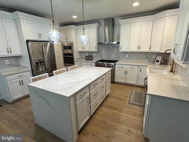 kitchen featuring high end appliances, white cabinets, wall chimney exhaust hood, a kitchen island, and recessed lighting
