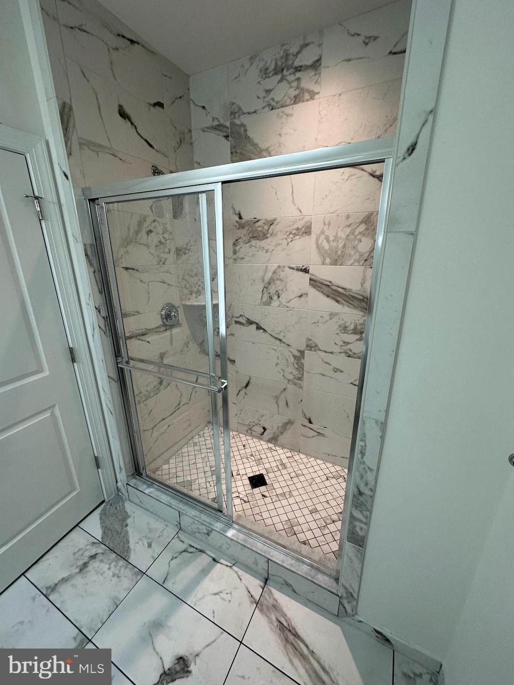 full bathroom with marble finish floor and a stall shower