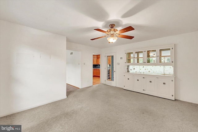 empty room featuring light carpet, baseboards, and a ceiling fan