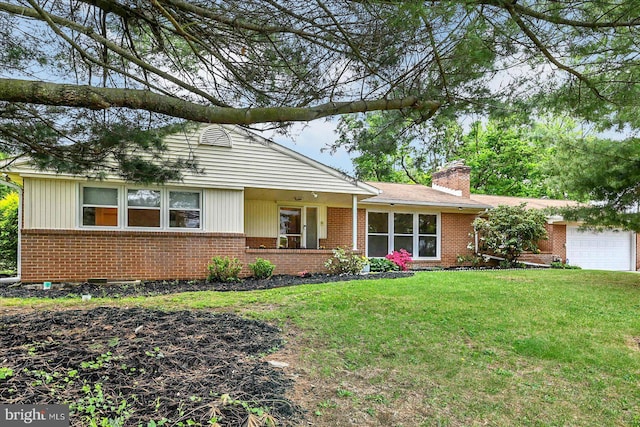 ranch-style home featuring a chimney, a front yard, brick siding, and an attached garage