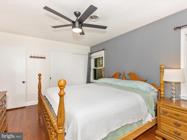 bedroom with wood finished floors, a closet, baseboards, visible vents, and a ceiling fan