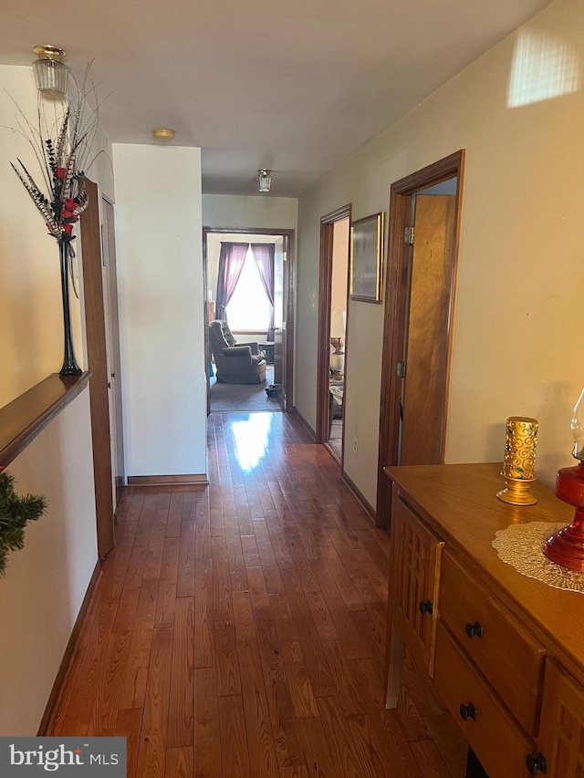 corridor with baseboards and dark wood-style flooring