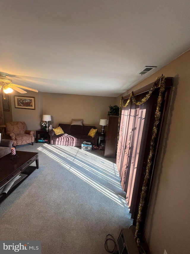 carpeted living area with visible vents and ceiling fan