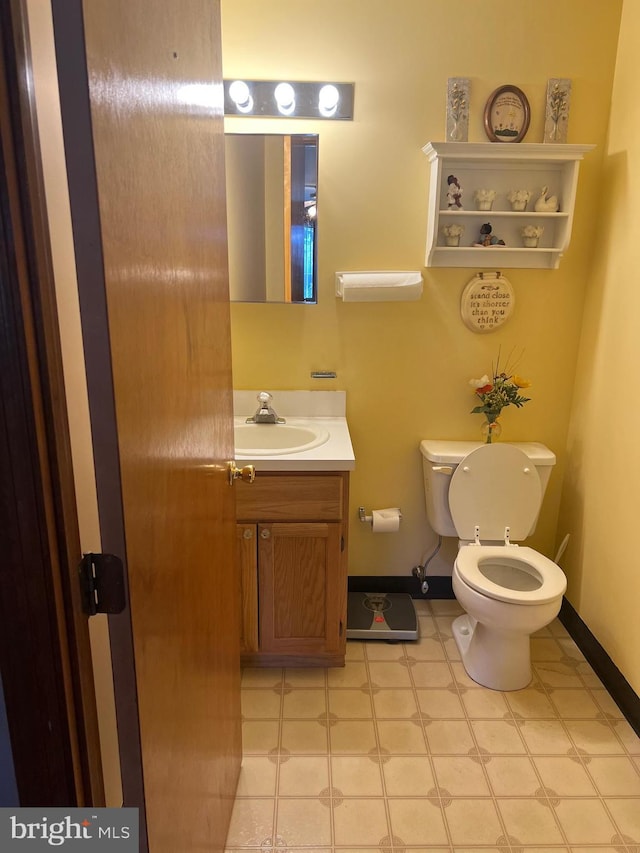 bathroom featuring toilet, vanity, tile patterned floors, and baseboards