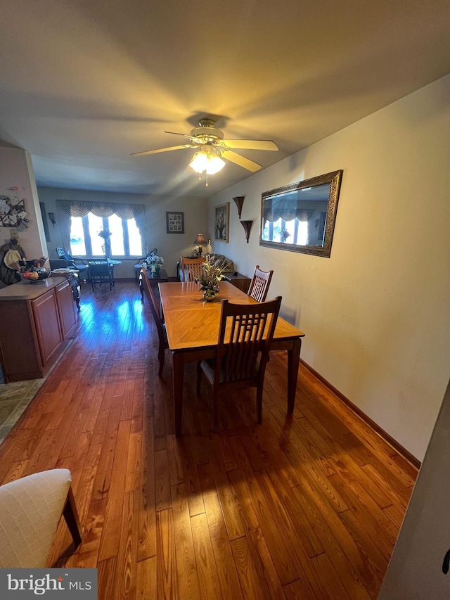 dining area featuring a ceiling fan, baseboards, and wood-type flooring