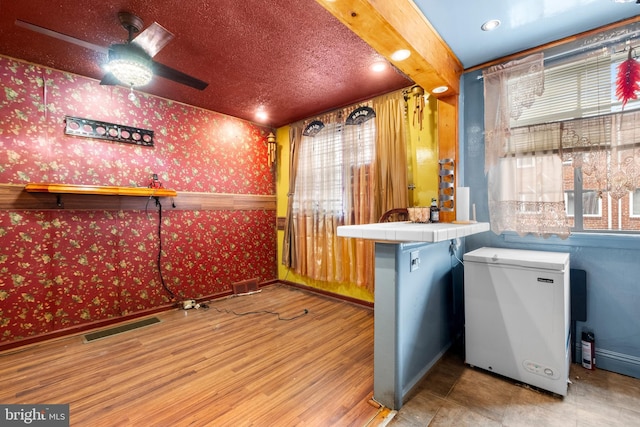 bar with wallpapered walls, fridge, visible vents, and a ceiling fan