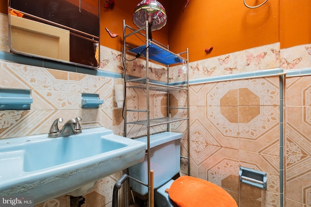 half bath featuring tile walls, a sink, and toilet