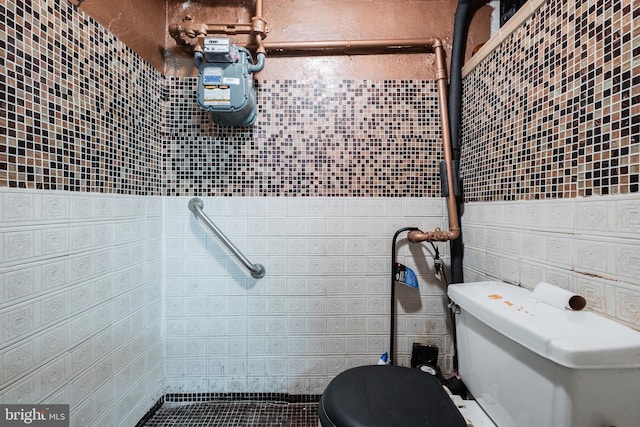bathroom with toilet and tile walls
