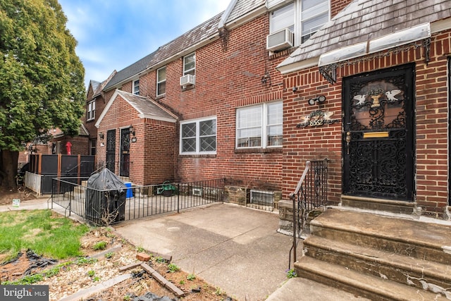 exterior space with brick siding, cooling unit, and fence
