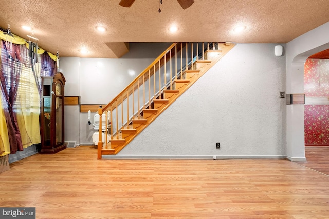 below grade area featuring a ceiling fan, wood finished floors, a textured ceiling, and stairway
