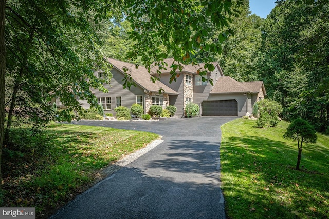 view of front of property with driveway, a front yard, and stone siding