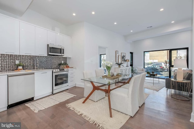 kitchen featuring decorative backsplash, recessed lighting, white cabinetry, and appliances with stainless steel finishes