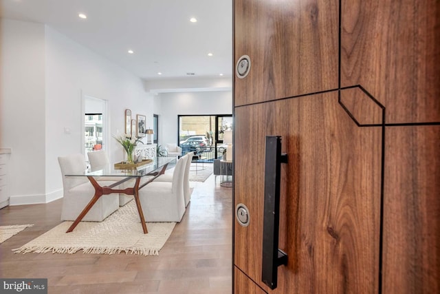 hallway featuring baseboards, wood finished floors, and recessed lighting