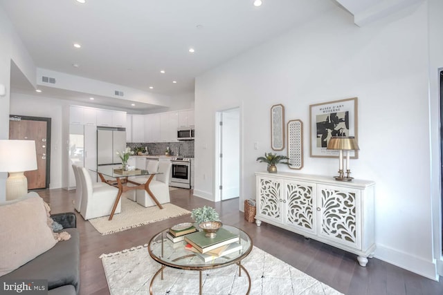 living room featuring baseboards, dark wood-style flooring, visible vents, and recessed lighting