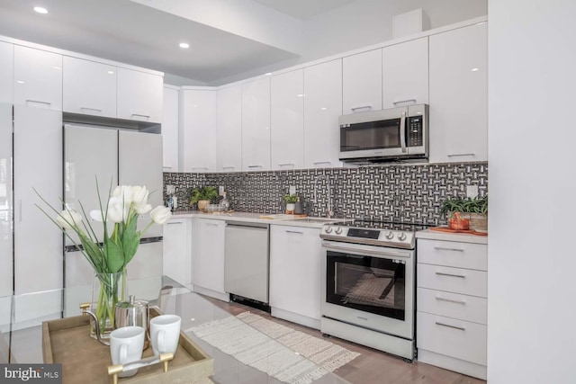 kitchen featuring white cabinets, stainless steel appliances, light countertops, and decorative backsplash